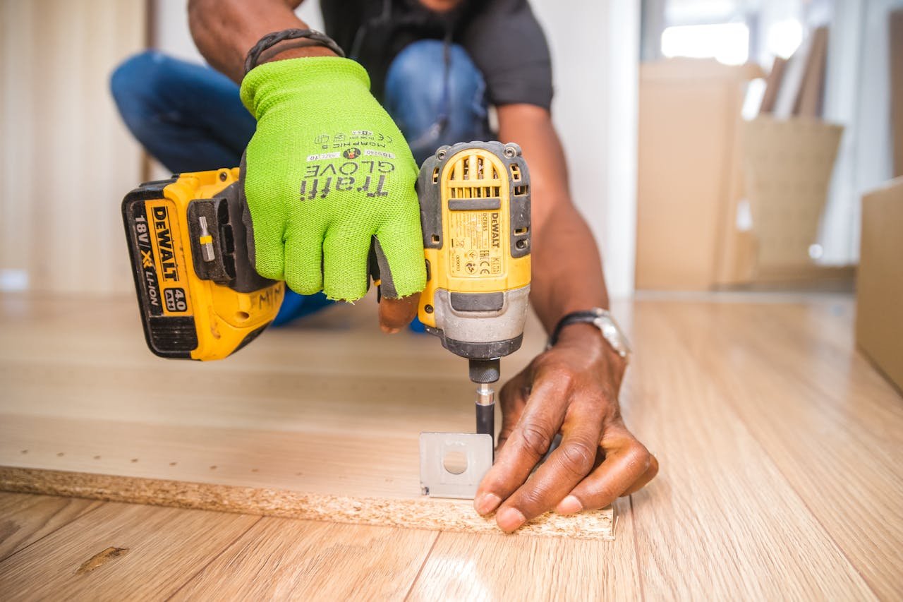 services-01 Man using a power drill for home improvement on a wooden floor with precision.