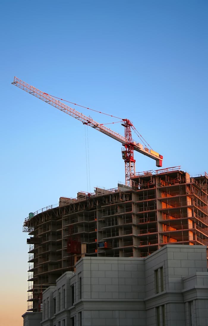journey Tower crane on a high-rise building under construction at sunset, showcasing modern urban development.